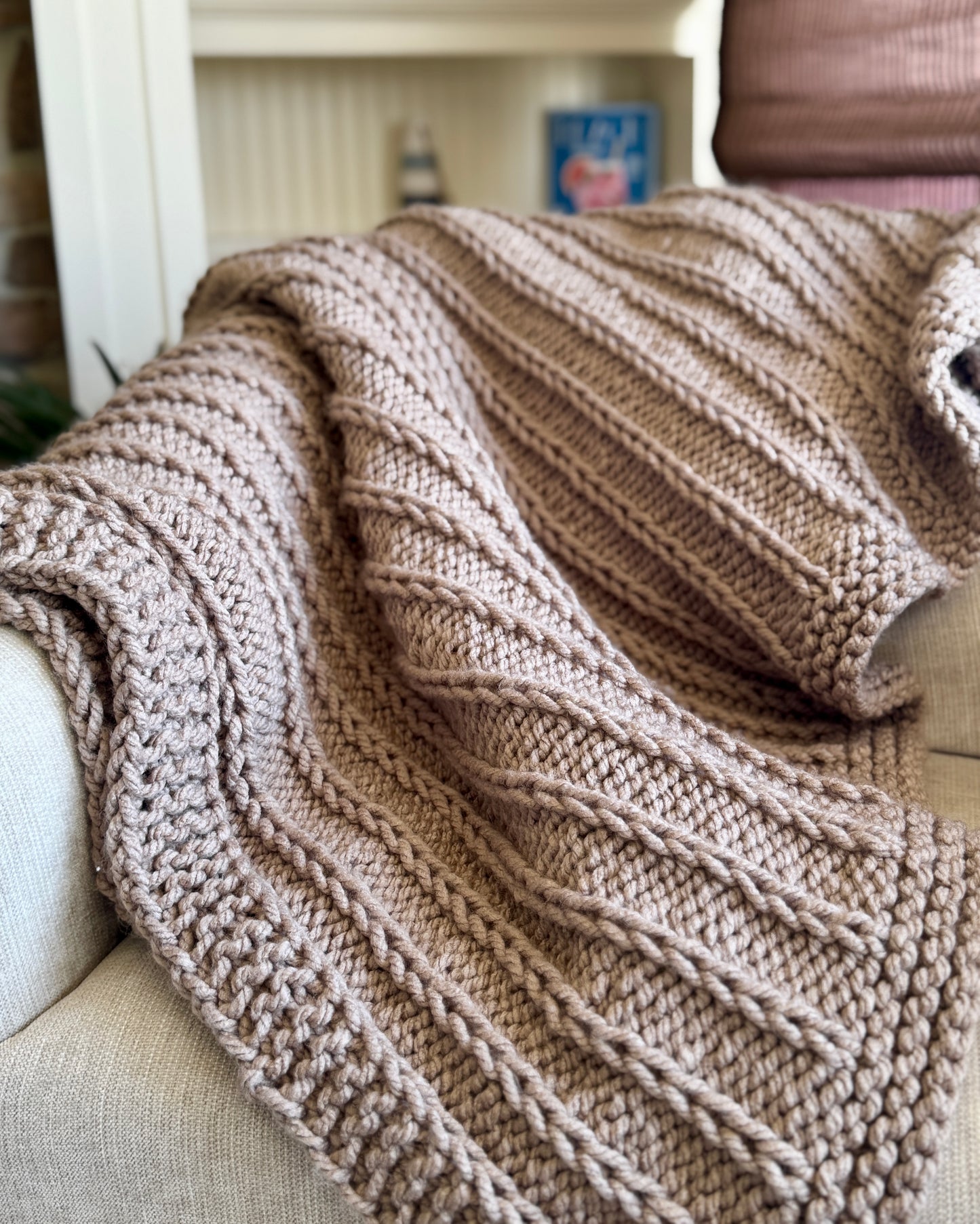 Knitted blanket draped over a sofa with a blurred background