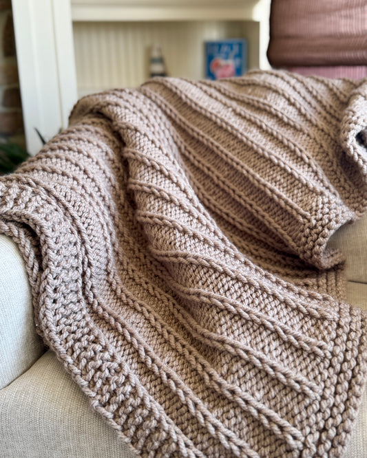 Knitted blanket draped over a sofa with a blurred background